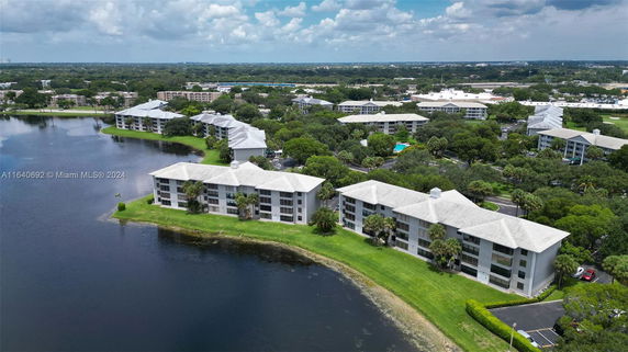 Aerial view of a residential complex by a lake with multiple buildings and green spaces.