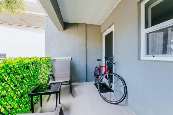 Outdoor balcony area with a chair, table, and a bicycle.