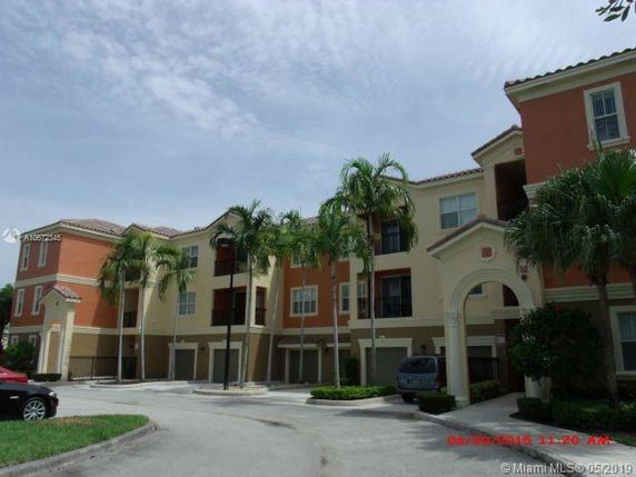 Front view of a multi-story residential building with arches and palm trees.