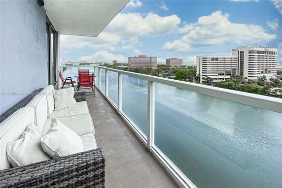 Panoramic view from a balcony showing distant buildings and a water body.