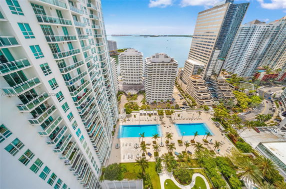 Panoramic view of high-rise buildings with a swimming pool and waterfront in the background.