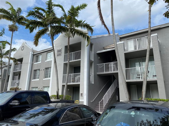 Front view of a modern apartment building with multiple balconies and a central staircase.