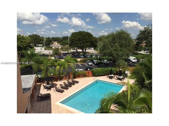 View of an outdoor swimming pool with lounge chairs and surrounding greenery.