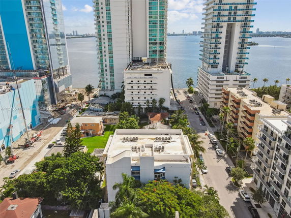 Aerial view of tall buildings near a waterfront with other residential structures.