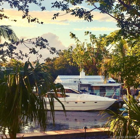 View of a boat docked near a structure surrounded by trees and water.