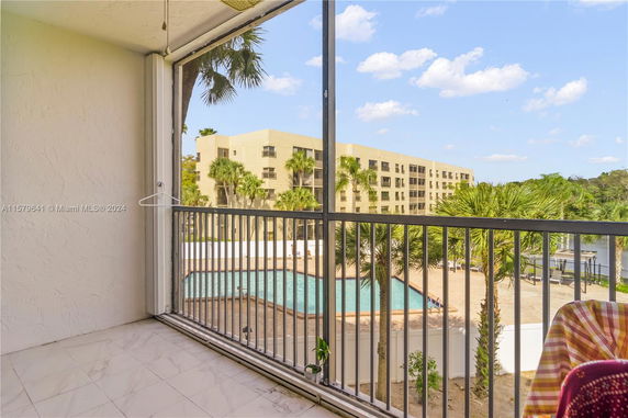 Balcony view showing a swimming pool and a multi-story building.