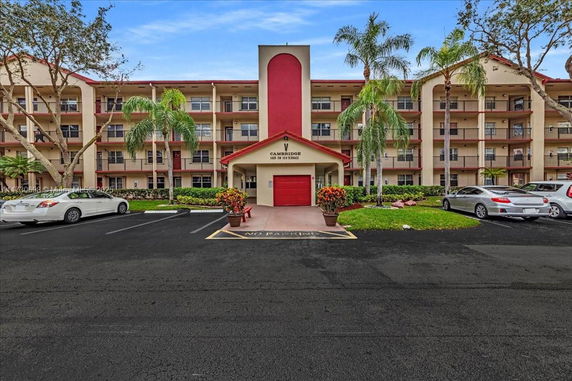Front view of a multi-story building with balconies and a red entrance canopy.