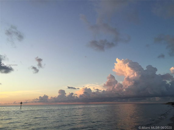 View of the ocean with scattered clouds at sunset.