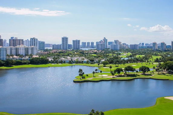 View of a cityscape with skyscrapers surrounding a lake and golf course.