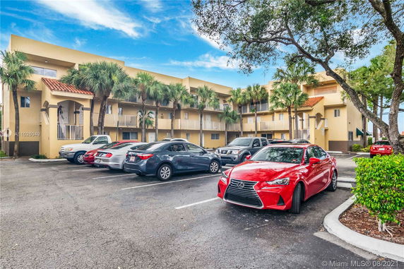 Outdoor parking area in front of a multi-story building with balconies.