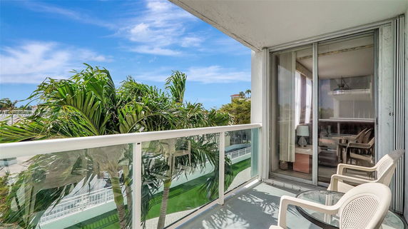 Balcony view with outdoor furniture and palm trees.
