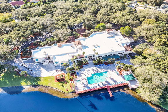 Aerial view of a large building with a swimming pool and surrounding greenery.