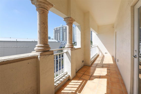 View from a balcony with terracotta tiles and decorative columns, overlooking nearby tall buildings.