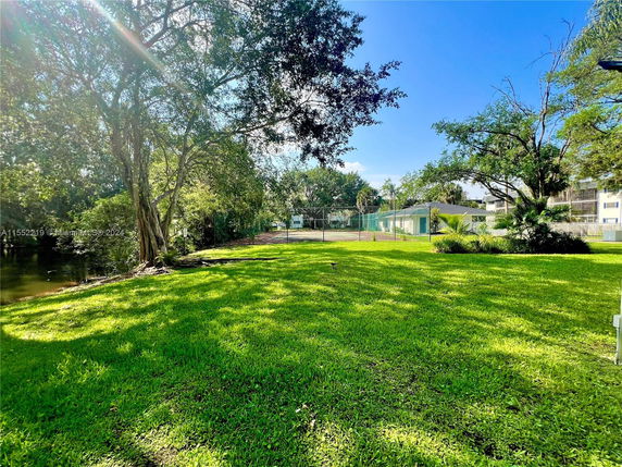 View of a grassy area with trees and a fenced building in the distance.