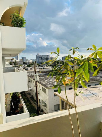 View from a balcony showing nearby buildings and a cloudy sky.