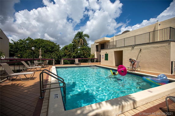 Outdoor swimming pool area with lounge chairs and surrounding trees.