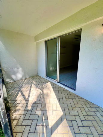 Exterior view of a building with a sliding glass door and a tiled patio.