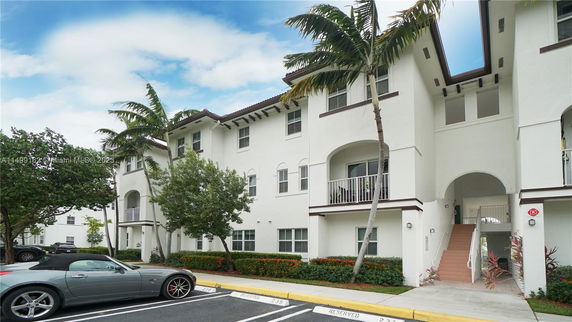 Front view of a multi-story residential building with balconies and an arched entrance.