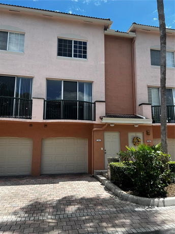 Front view of a multi-story townhouse with two garages and balconies.