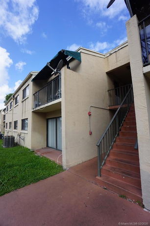 Front view of a two-story residential building with exterior stairs.