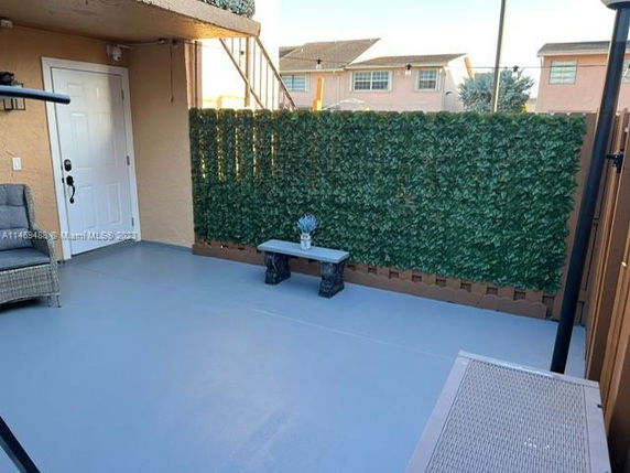 View from a building showing a small enclosed patio area with a bench and artificial greenery.