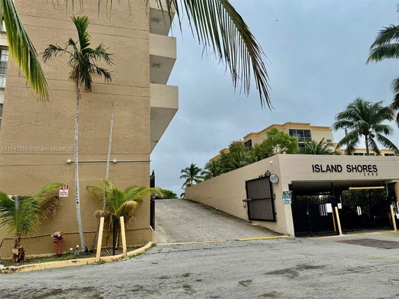 Front view of a multi-story building named Island Shores with a gated entrance.