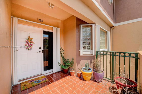 Front view of a house entrance with a white door and terracotta tiles.
