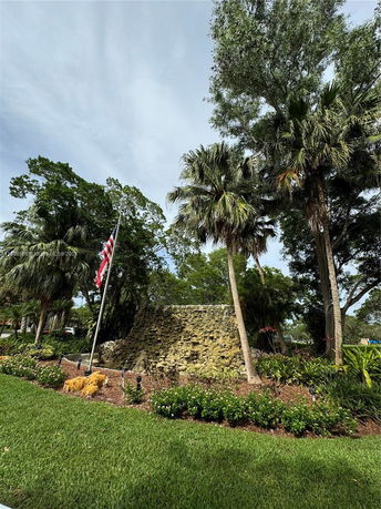 Stone monument surrounded by palm trees and greenery