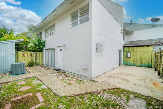 Front view of a two-story house with a paved walkway and fenced yard.