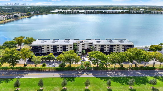 Aerial view of a multi-story apartment building by a large body of water.