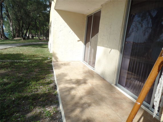 Side view of a building with a tiled patio and sliding glass doors.