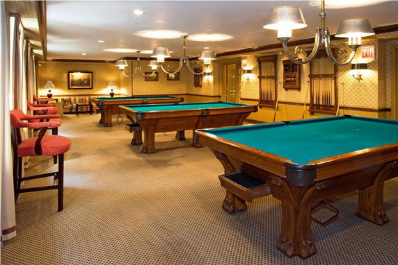 Room with multiple billiard tables and seating area