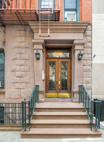 Front view of a building entrance with stone steps and wooden doors.