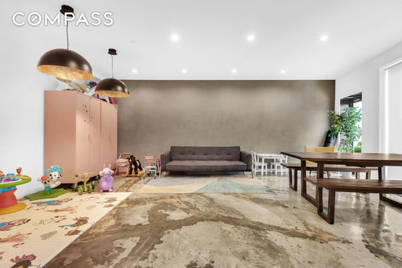 Room with a couch, children's toys, and play mats on a polished concrete floor.