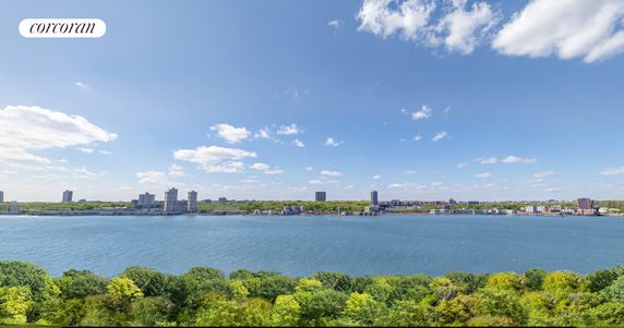 Panoramic view of a river with buildings and greenery along the shoreline.