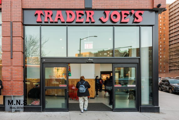 Front view of a brick commercial building with large glass entrance, labeled Trader Joe's.