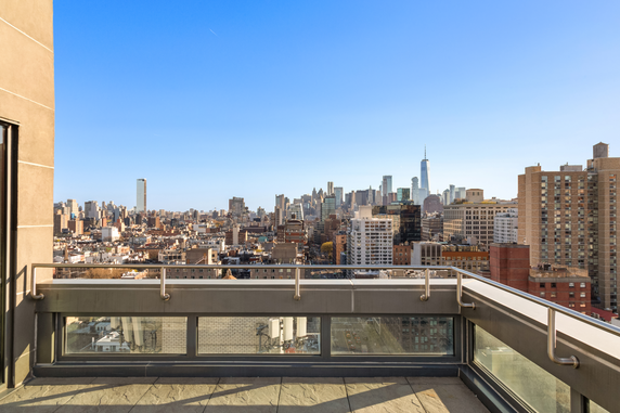 Panoramic view of a cityscape from a rooftop terrace with railing.