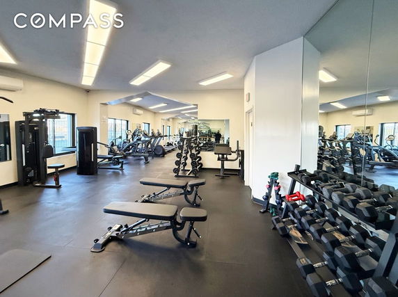 Interior view of a gym with exercise equipment and weights.