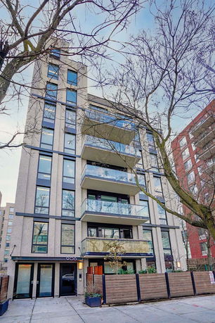 Front view of a modern multi-story apartment building with glass balconies.