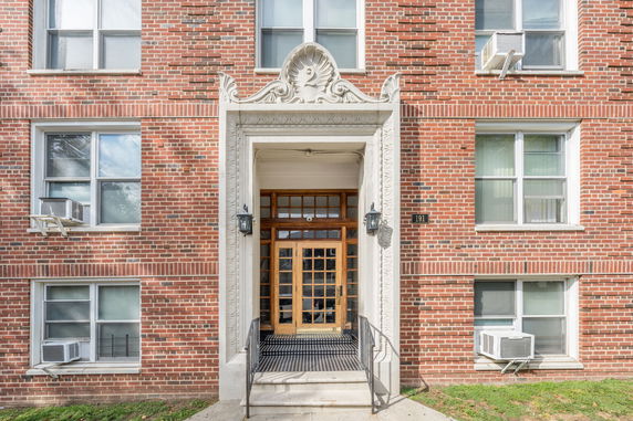 Front view of a brick apartment building with decorative entryway and multiple windows.