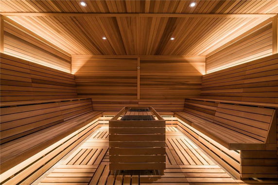 Interior view of a wooden sauna room with benches and central heating element.
