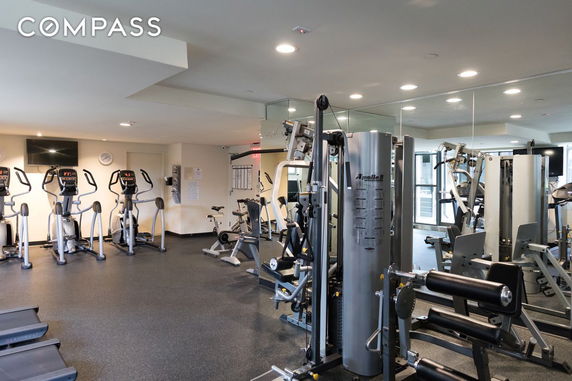 Indoor gym area equipped with exercise machines and weights.