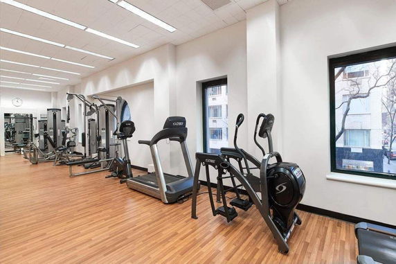 Interior view of a gym room with exercise machines and wooden flooring.