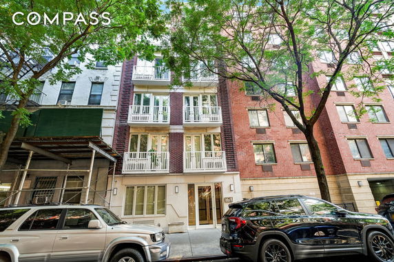 Front view of a multi-story residential building with balconies and large windows.