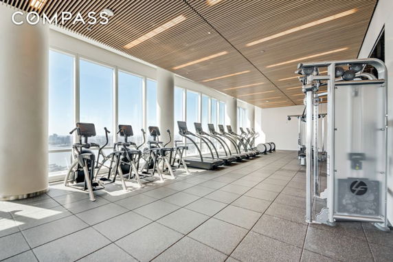Indoor fitness gym with exercise machines and large windows.