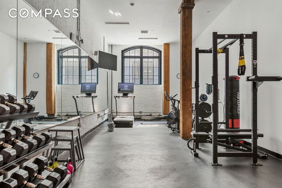 Indoor gym area with workout equipment and large mirrors.