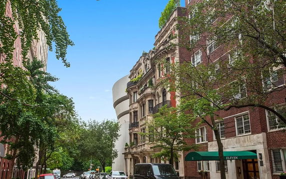 Street view of a multi-story residential building with balconies and an adjacent modern building.