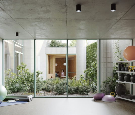 Interior view of a room with fitness equipment and large windows overlooking a courtyard.