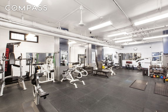 Indoor gym area with various exercise equipment and mirrors.