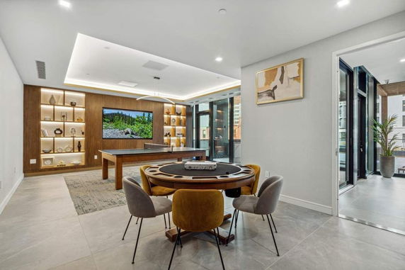 Interior of a room with a pool table, poker table, and built-in shelves.